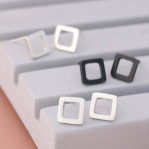 Square silver stud earrings in polished, matte, and oxidised finishes on grey dish