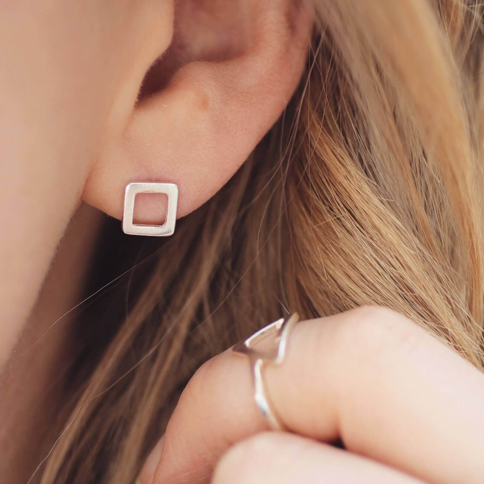Square silver stud earrings worn on ear, elegant small square stud earrings