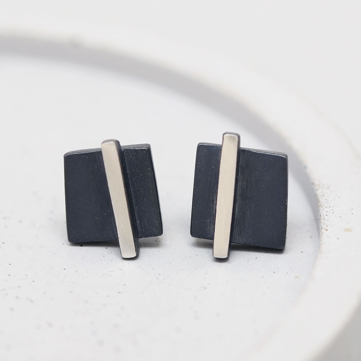 Detailed shot of small black stud earrings on a grey dish showing texture and finish, great Christmas stocking filler.