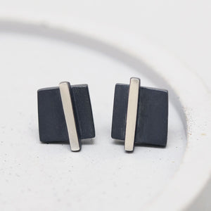 Detailed shot of small black stud earrings on a grey dish showing texture and finish, great Christmas stocking filler.