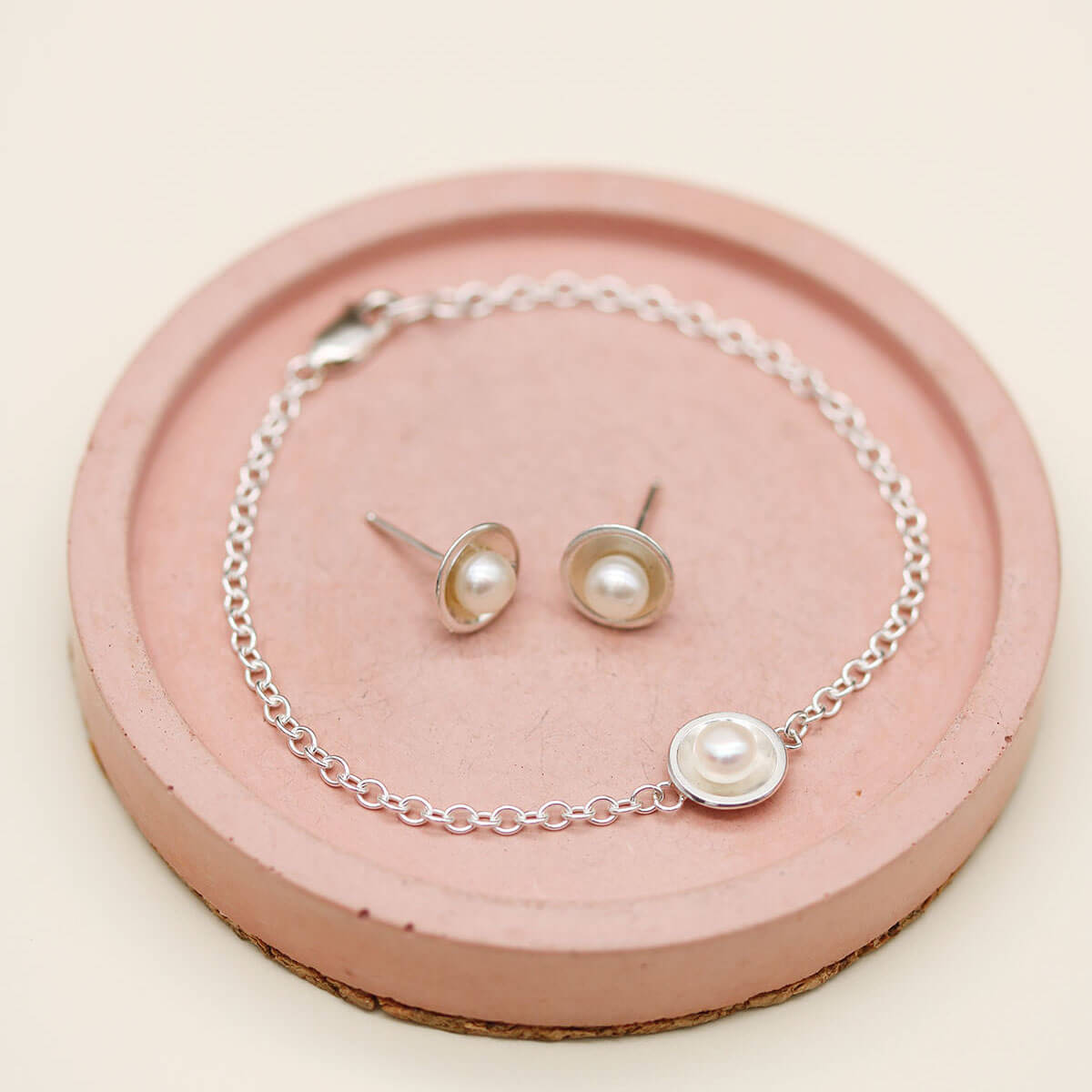 Handmade sterling silver and pearl bracelet photographed with coordinating pearl stud earrings from the matching jewellery collection.