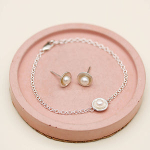 Handmade sterling silver and pearl bracelet photographed with coordinating pearl stud earrings from the matching jewellery collection.