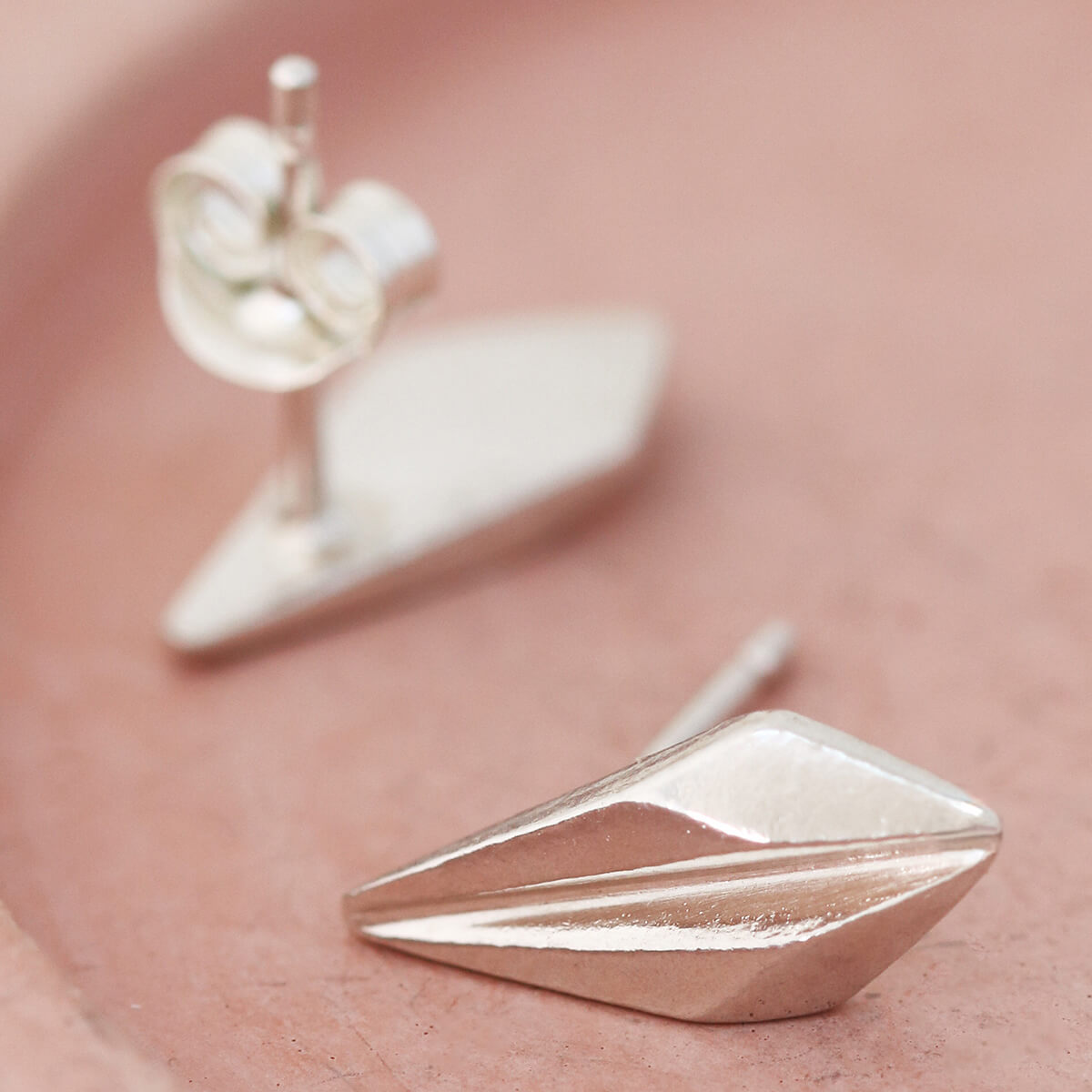 Pair of silver art deco stud earrings on a pink dish, showing the elegant ridged design of these art deco style earrings suited for bridesmaids or special occasions.