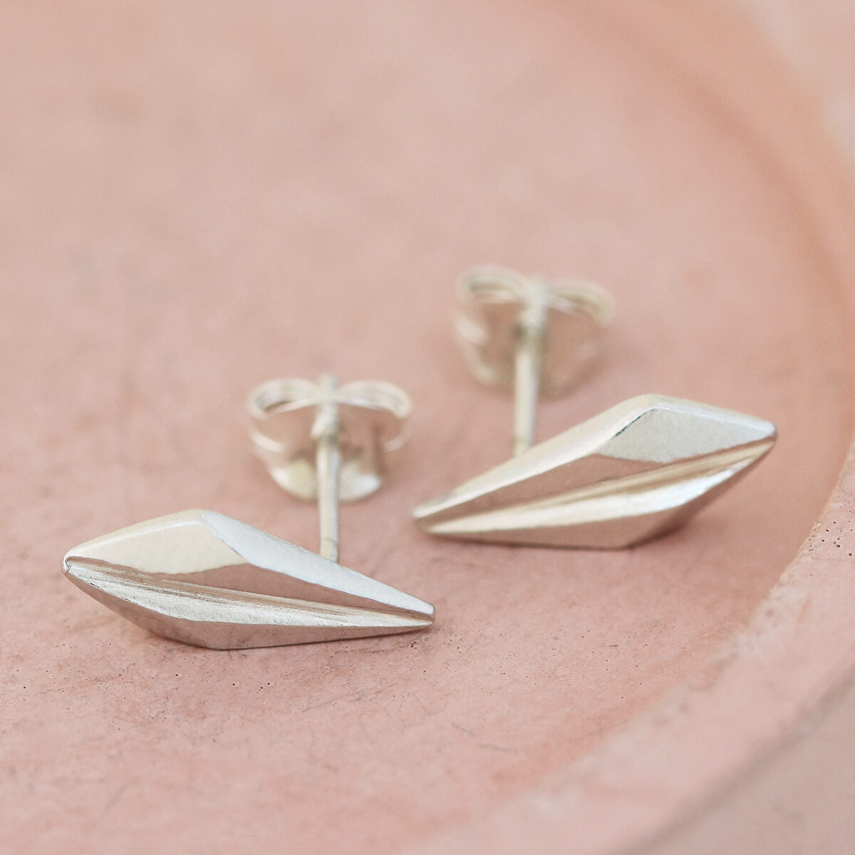 Product close-up of art deco style earrings on a pink dish, demonstrating the refined silver geometry ideal for brides, bridesmaids, and special celebrations.