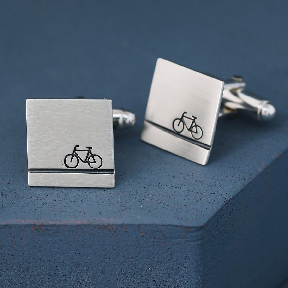 Sterling silver bike cufflinks photographed on deep blue background with polished edges, ideal cycling gifts for him or anniversary presents.