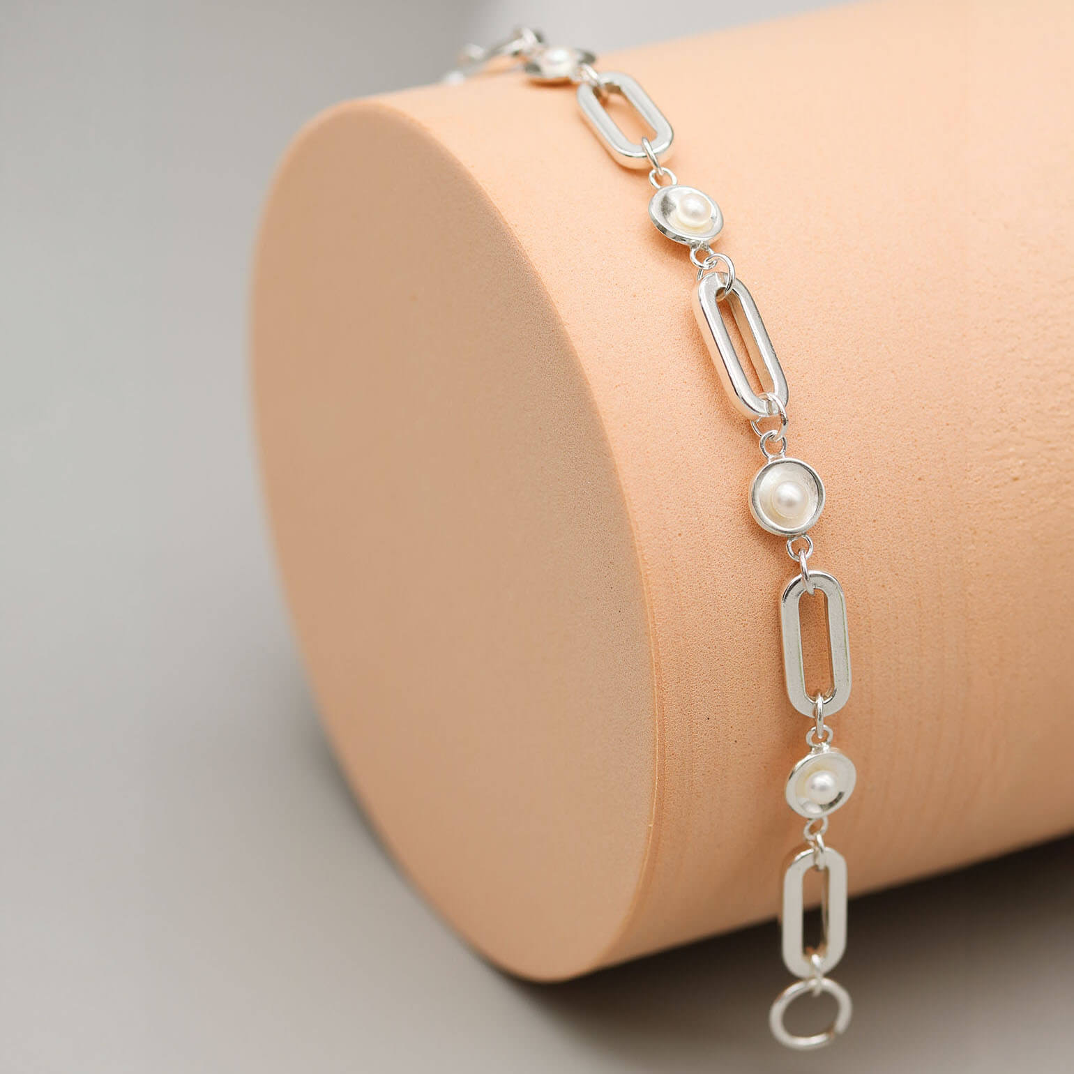 Close up of a handmade sterling silver pearl chain bracelet highlighting polished pearl settings and genuine freshwater pearls.