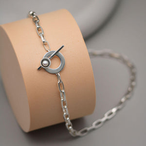 Close up of a handmade chunky pearl necklace highlighting the oxidised sterling silver pearl setting, T-bar toggle and bold rectangular trace chain.