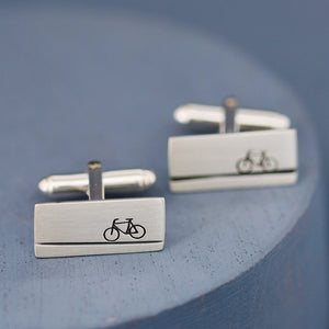 Pair of handmade cycling cufflinks on deep blue background, timeless sterling silver gift for bicycle lovers, cyclists, and sports enthusiasts alike.
