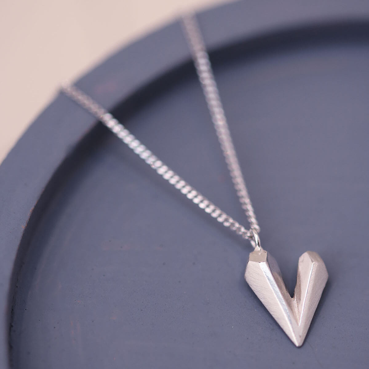 Heart shaped necklace on a blue dish, a timeless dainty heart necklace crafted in solid sterling silver