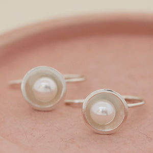Sterling silver freshwater pearl drop earrings displayed to highlight their elegant floating profile below the ear.