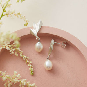 Detailed macro shot of geometric Art Deco silver fan paired with pearl drop, unique handcrafted gift for pearl lovers.