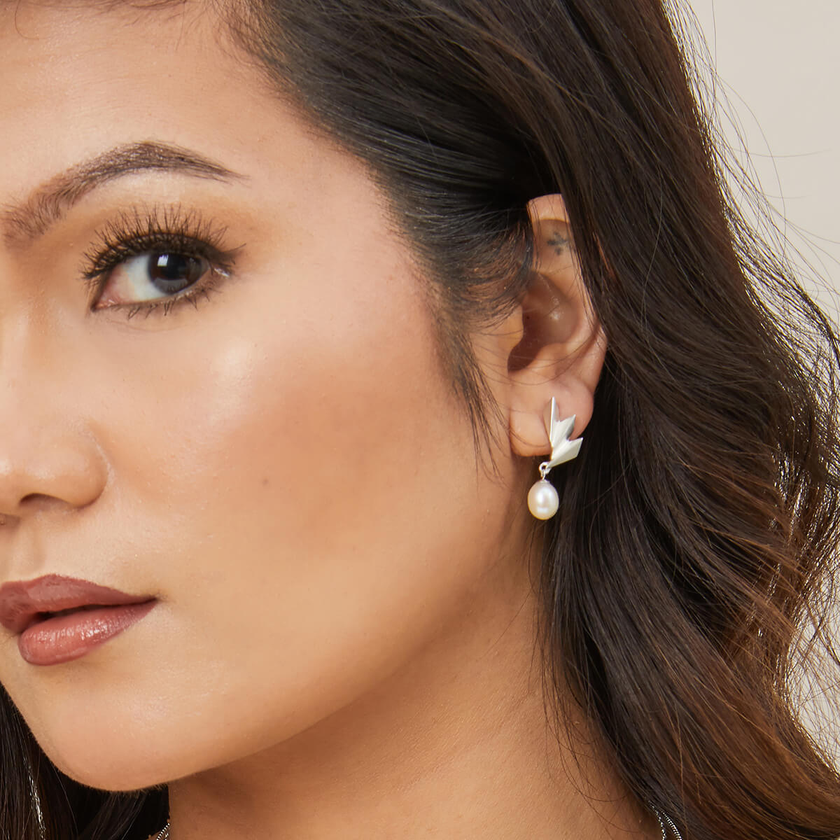 Model wearing sterling silver drop pearl earrings styled with a v-neck outfit, perfect gift for bridesmaids or anniversaries.