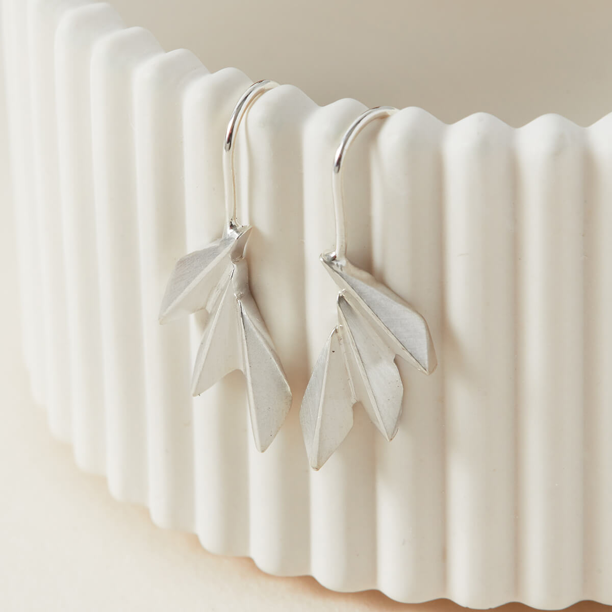 Art deco drop earrings on a white dish showing the crisp geometric fan design; perfect fan drop earrings for wedding day jewellery gifts.