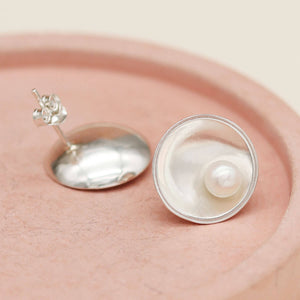 Handmade sterling silver pearl stud earrings with genuine freshwater pearls photographed on a pink ceramic dish.