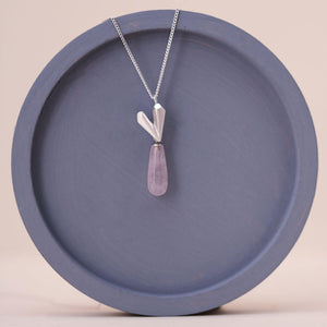 Sterling silver heart necklace on a blue dish, showcasing a pink quartz heart pendant suspended from a fine silver chain.