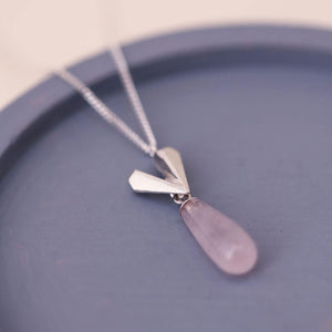 Pink quartz heart pendant on a sterling silver heart necklace photographed on a blue dish, highlighting the faceted heart and teardrop gemstone.