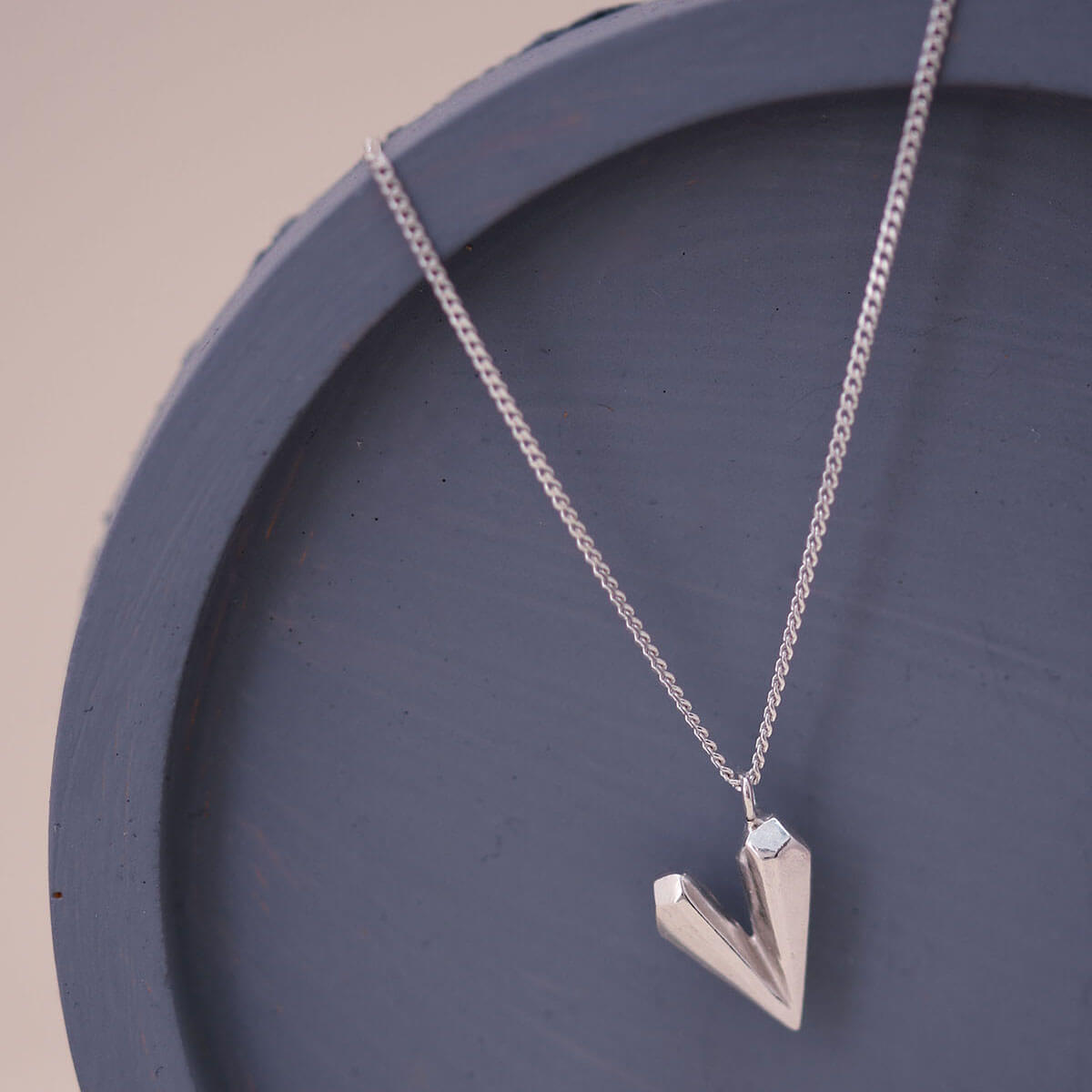 Sterling silver dainty heart necklace on a blue dish, featuring a faceted heart shaped charm designed for everyday elegance