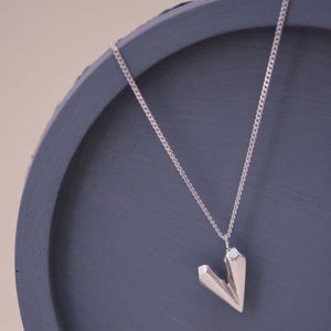Sterling silver dainty heart necklace on a blue dish, featuring a faceted heart shaped charm designed for everyday elegance