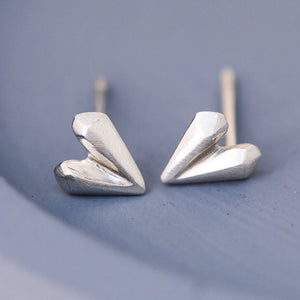 Close up of love heart earrings in sterling silver on blue dish, delicate silver heart stud earrings for second piercings
