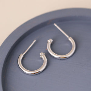 Silver hoop earrings without charm styled on a blue dish, versatile sterling silver hoops worn alone