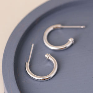 Silver hoop earrings without charm on a blue dish, minimalist sterling silver charm hoops worn as classic everyday hoops