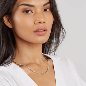 Silver link necklace styled on a woman, showing the contemporary geometric design and fluid movement of the individual links