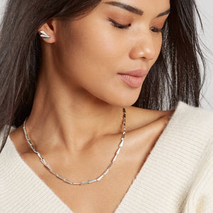 Woman wearing a contemporary sterling silver link necklace, showing the bold geometric Art Deco-inspired design and sculptural movement