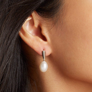 Model wearing silver dangle pearl earrings, showing the elegant drop and soft movement against the jawline.