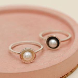 Polished sterling silver pearl ring worn as part of a ring stack
