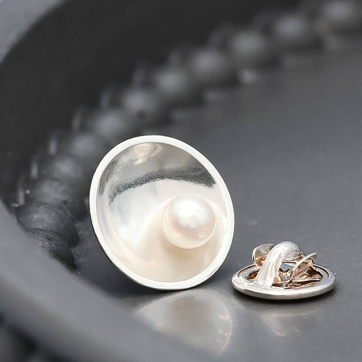 Sterling silver pearl tie pin displayed on a dark grey background, designed for weddings, anniversaries and formal occasions.