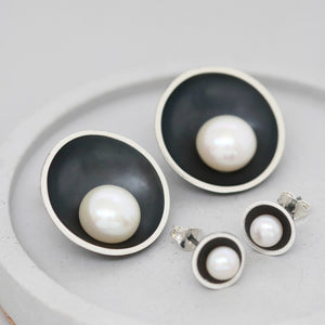 Large and small black pearl stud earrings shown side by side