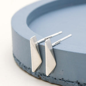 Tiny geometric sterling silver stud earrings for a second hole, handmade small silver studs displayed on a deep blue dish