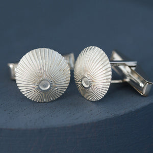 Domed round cufflinks in polished sterling silver with laser-engraved sunburst pattern on deep blue backdrop – special gift for husband.