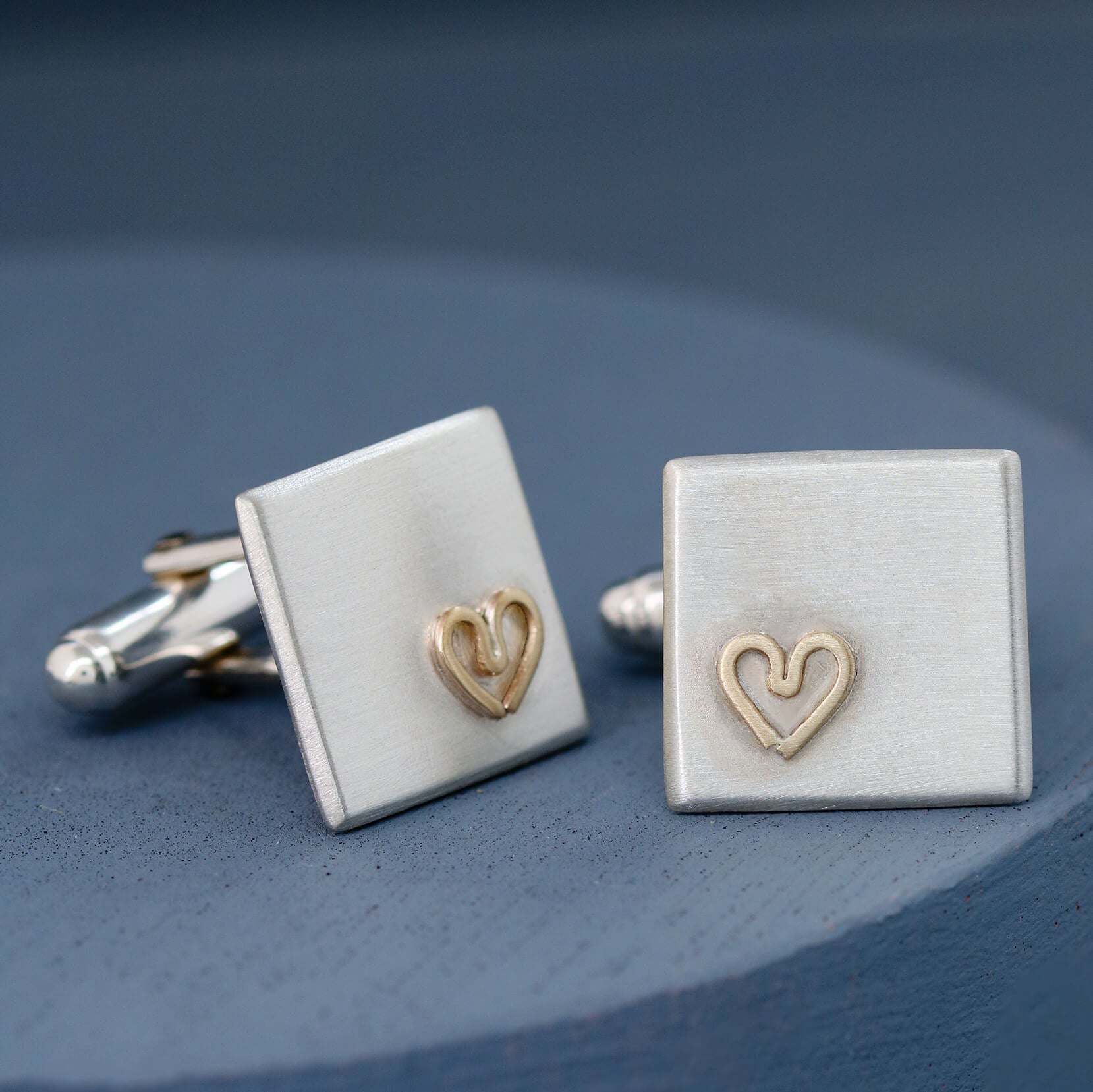 Handmade cufflinks on a deep blue background showing their minimalist design and gold heart accent — thoughtful gift for husband.