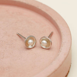 Small sterling silver pearl studs with polished silver domes and freshwater pearls