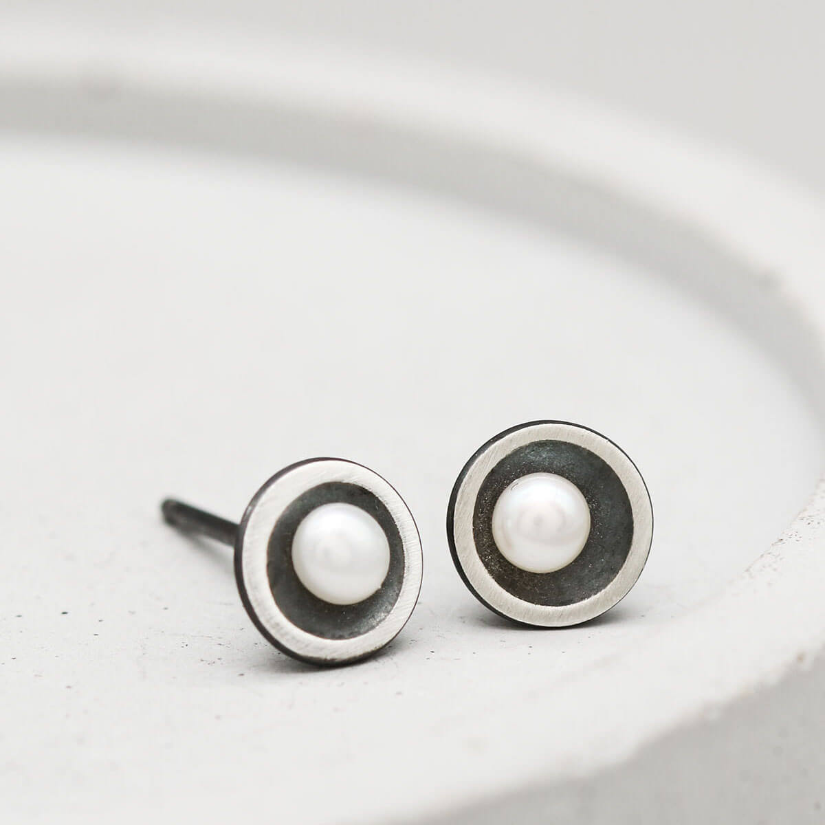 Petite black pearl stud earrings in oxidised sterling silver, designed for second piercings and everyday wear.