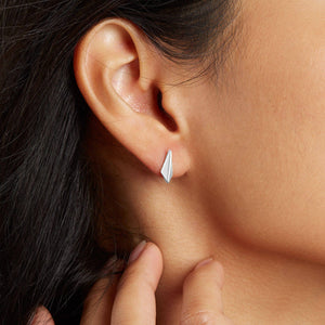 Woman wearing small sterling silver kite stud earrings, understated everyday silver studs with a geometric Art Deco-inspired design
