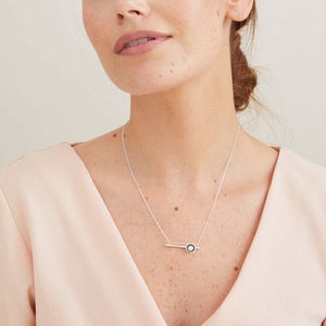 Handmade black geometric pearl necklace styled with layered silver chains for a modern everyday look.