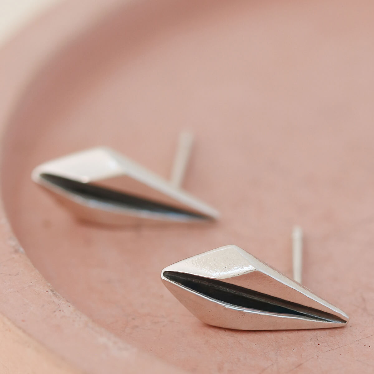Detailed view of art deco earrings studs on pink dish ideal for Art Deco lovers.