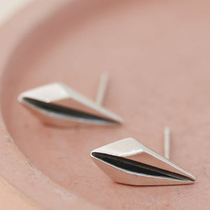 Detailed view of art deco earrings studs on pink dish ideal for Art Deco lovers.