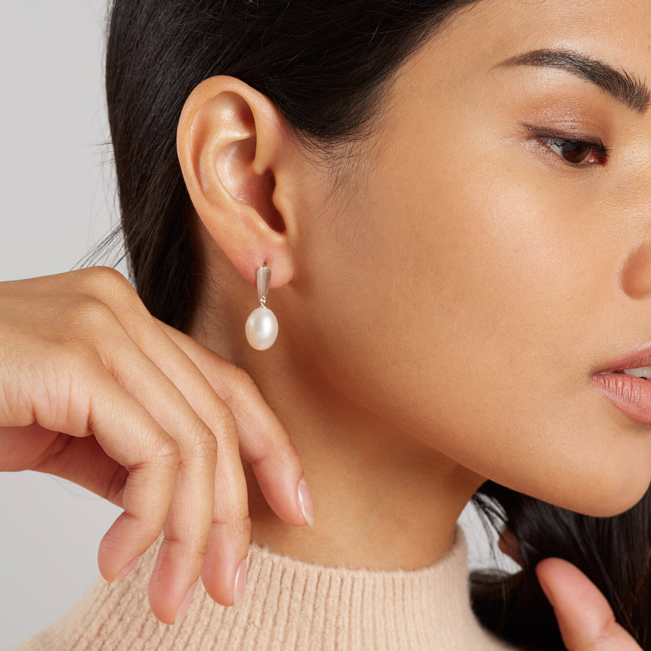 Side profile of model wearing sterling silver dangle pearl earrings, illustrating their length and comfortable fit.